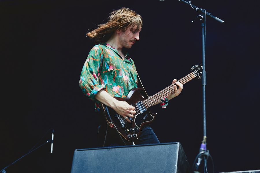 Bassist in a green patterned shirt, hair flying