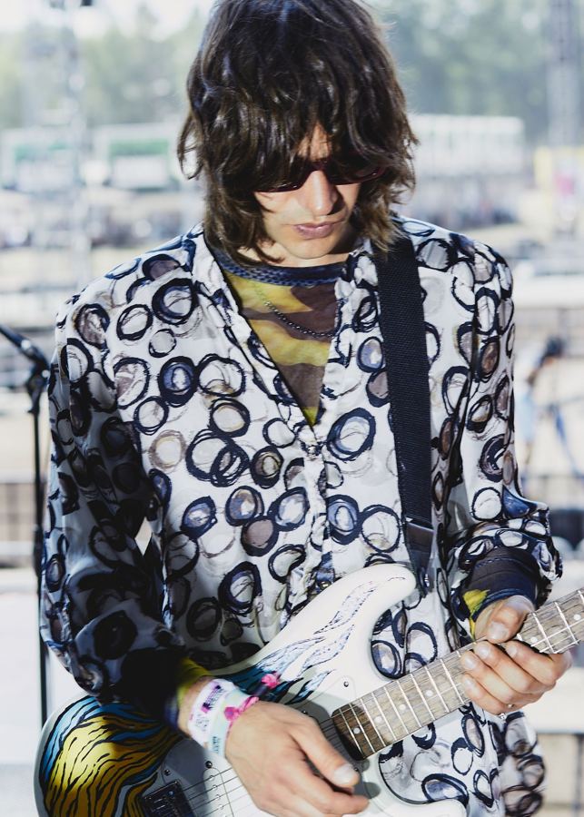 Guitarist in a circle-print shirt playing a painted Stratocaster