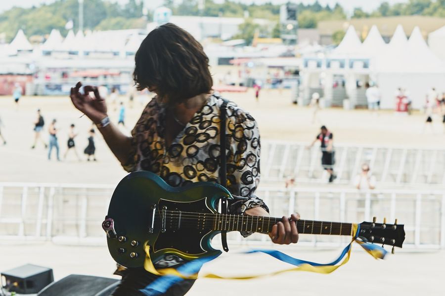 Guitarist with Ukrainian ribbons, festival field behind